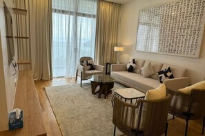 Un salon moderne avec un canapé, des fauteuils, une table basse et un grand mur décoré d’un jeu de mots.