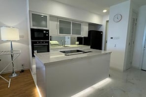 Una cocina moderna con una isla central, electrodomésticos integrados y un reloj en la pared.