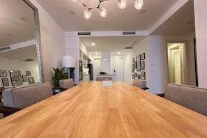 A conference room with a long wooden table, chairs, a chandelier, and framed pictures on the walls. - JD Luxury Lavanya Apartment (Langkawi)