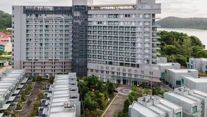 Un hotel de varios pisos con un diseño moderno, que cuenta con un jardín en la azotea y vistas a un lago.