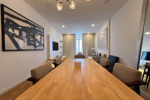 A conference room with a long table, chairs, a television, and a large abstract painting on the wall. - JD Luxury Lavanya Apartment (Langkawi)