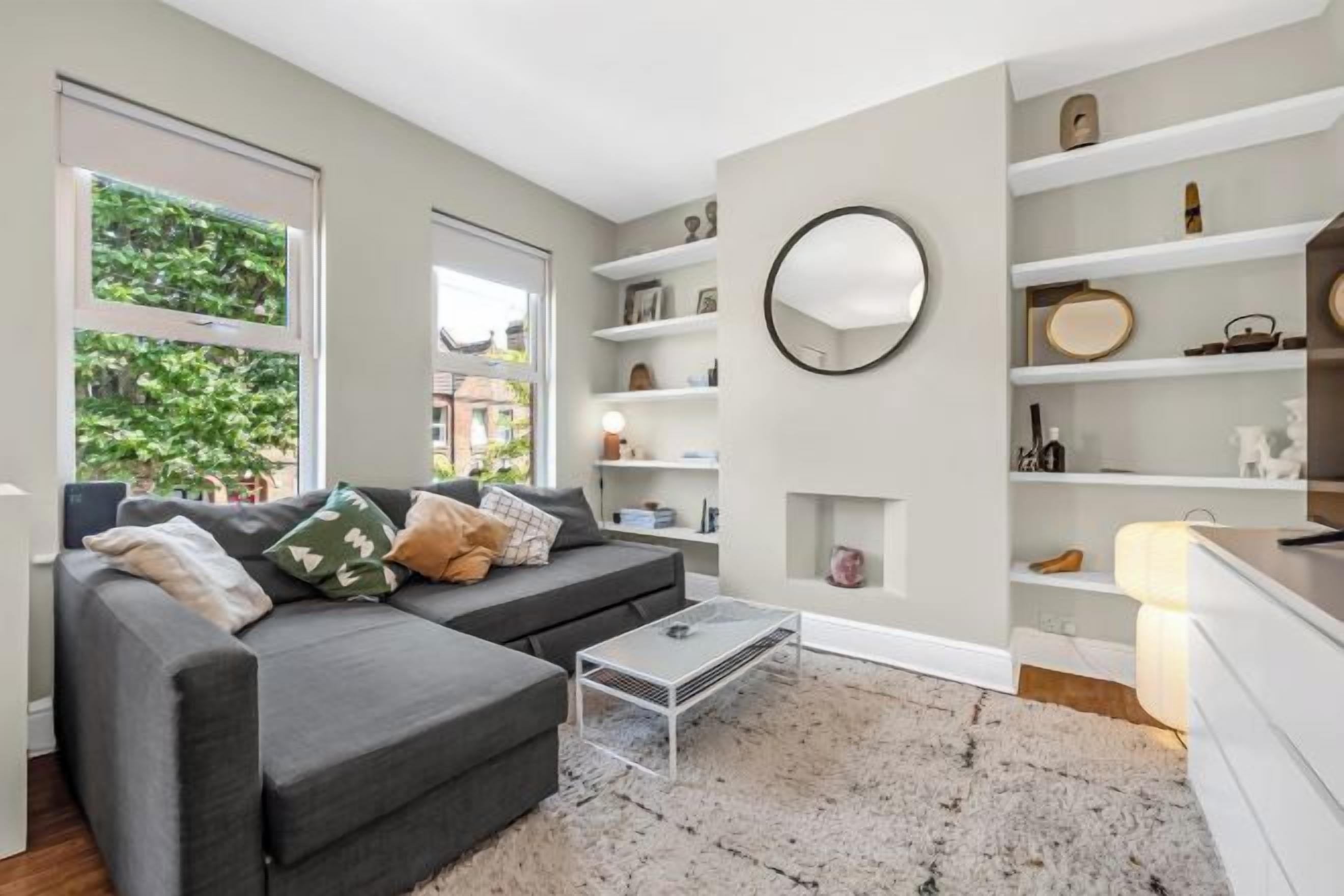 A modern living room with a grey sofa, a coffee table, and built-in shelving.