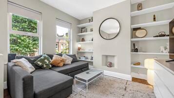A modern living room with a grey sofa, a coffee table, and built-in shelving.
