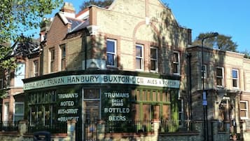 A building with a signboard advertising Truman Hanbury Buxton & Co. C.C. Ales & Porter, including Truman's Noted Ales & Stout, Truman's Barrelled Ales & Stout, and Bottled Beers.