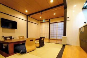 A traditional Japanese-style room with tatami flooring, a low table with cushions, and sliding doors. - Haku Flower's Seven (Kyoto)