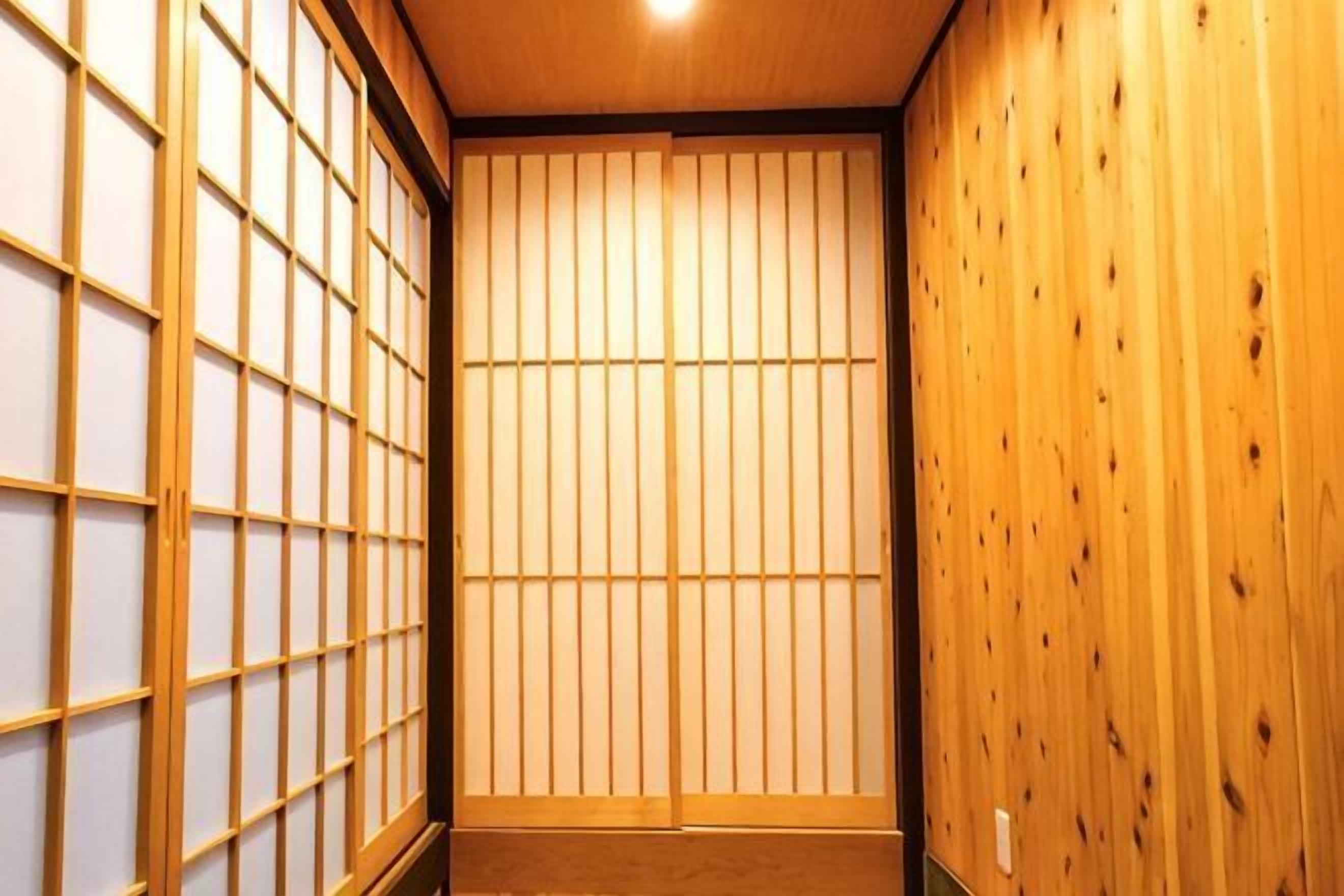 A traditional Japanese room with tatami flooring, shoji screens, and wooden paneling.
