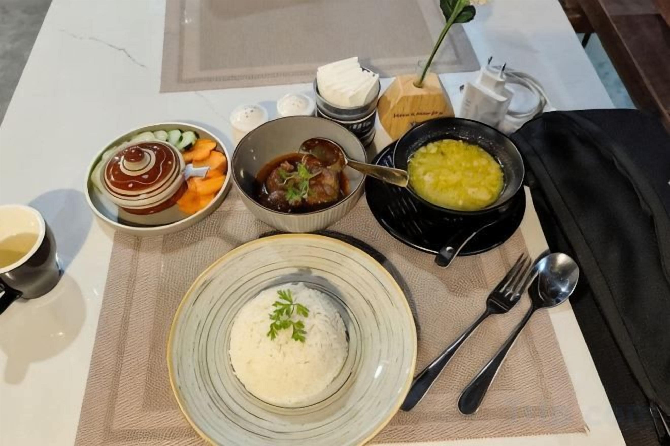 A table set with various dishes including rice, soup, and a bowl of what appears to be a stew or curry.