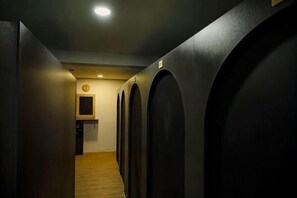 A hallway with arched doorways leading to individual rooms, a wooden floor, and a clock on the wall. - Hotel Lexi (Vientiane)