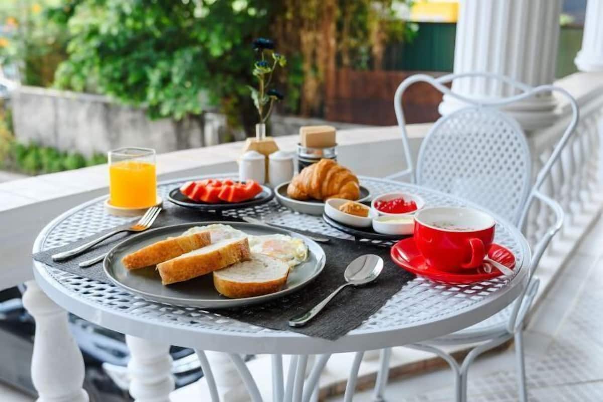 A round metal table with breakfast items including croissants, toast, strawberries, and a glass of orange juice.
