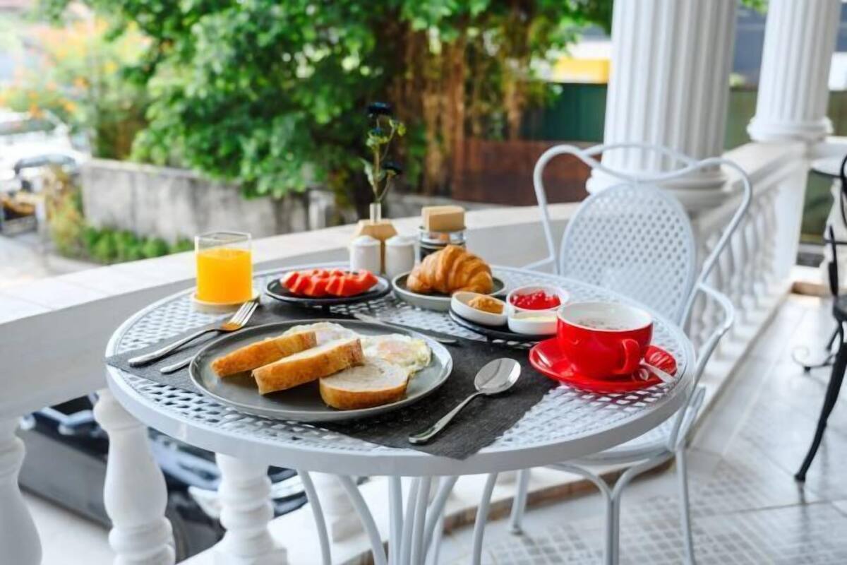 A round table with breakfast items, a glass of orange juice, a croissant, and a red cup.