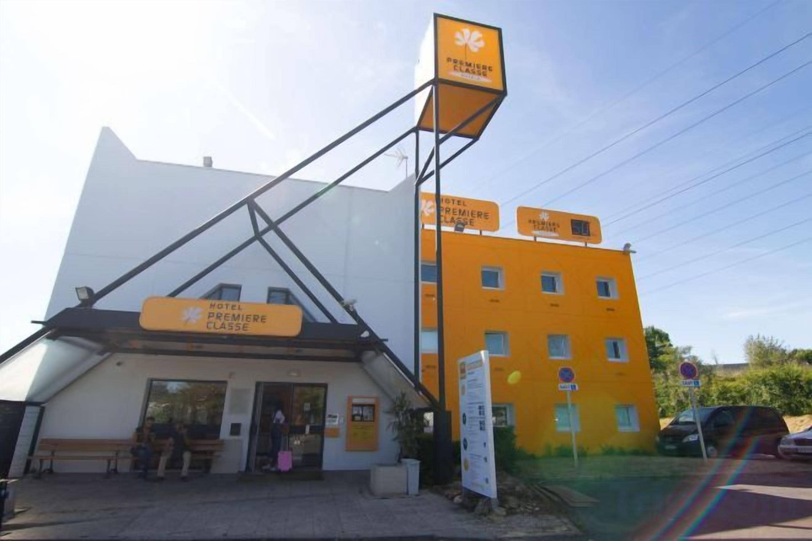 Een gebouw met een bord waarop hotel en les vermeld staan. Er zijn ramen en een deur te zien.