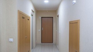 En smal hall med trädörrar på båda sidor, ett klinkergolv och en enkel vägg med en taklampa.