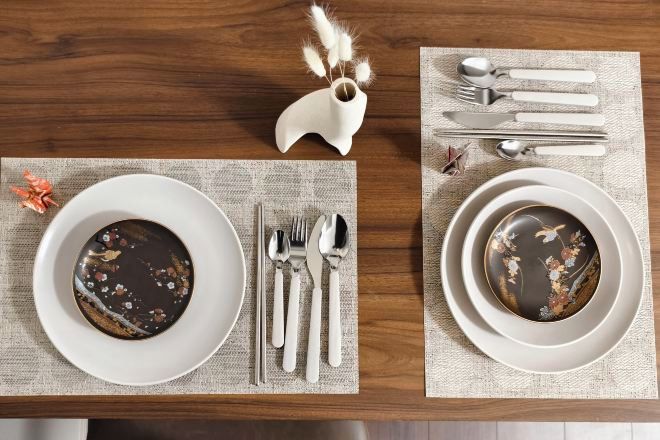 A dining table with two plates, each with a dessert and a set of cutlery.