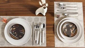 A dining table with two plates, each with a dessert and a set of cutlery.