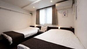 Una habitación de hotel con dos camas individuales, una ventana con cortinas, un teléfono en la pared y una pequeña planta en maceta.