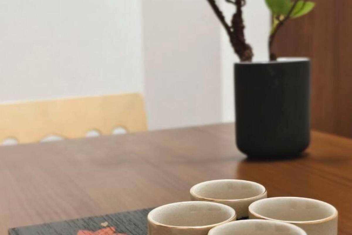 A table with four ceramic cups and a potted plant.