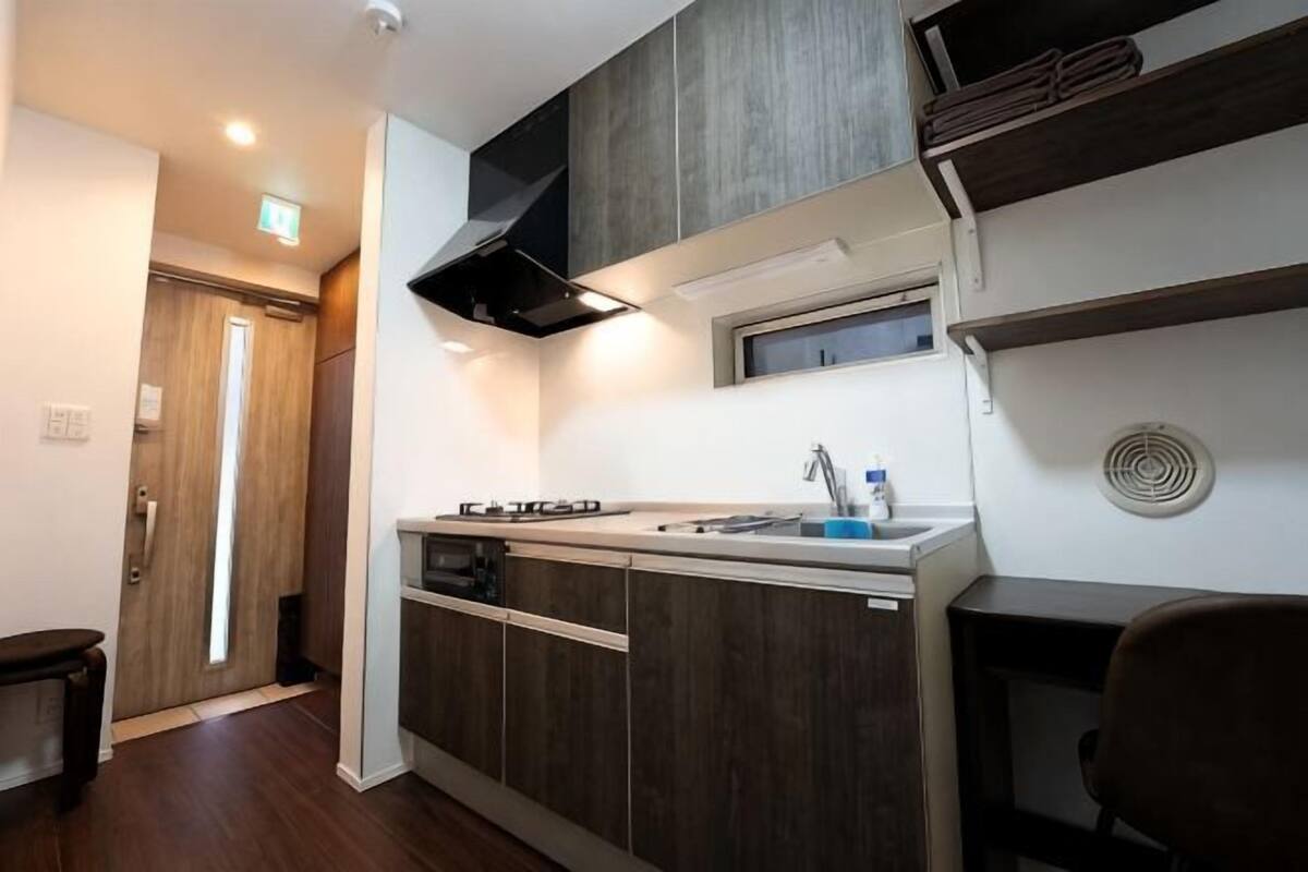 A compact kitchen with a built-in stove, sink, and ventilation hood.