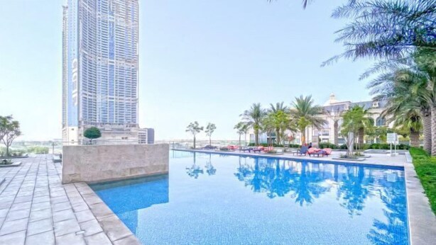 A swimming pool with lounge chairs and palm trees. - bnbme Classic 1BR 8 mins to Burj Khalifa (Dubai)