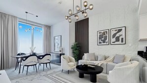 A modern living room with a sofa, coffee table, and dining area. - bnbme Classic 1BR 8 mins to Burj Khalifa (Dubai)
