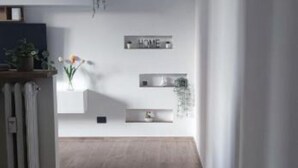 A modern interior with a minimalist design, featuring a wooden floor, white walls, and a 'HOME' sign. - Milan vacation home 15 minutes from the cathedral subway (Milano)