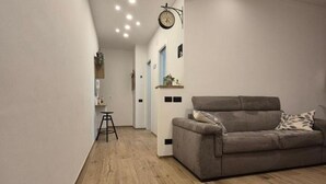A modern living room with a grey sofa, wooden flooring, and a small stool. - Milan vacation home 15 minutes from the cathedral subway (Milano)
