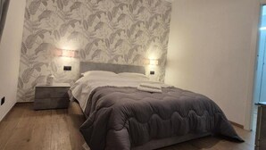 A bedroom with a bed, bedside tables, and a patterned wallpaper. - Milan vacation home 15 minutes from the cathedral subway (Milano)