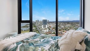 A bedroom with a large window offering a cityscape view. - Skyline Showdown - Views, Games & Vibes (Southport)