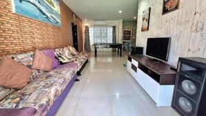 Una sala de estar con un sofá, televisor y altavoces.