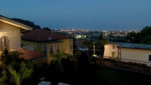 A rooftop with sun loungers, a pool, and a view of a cityscape at dusk. - Etna Villa Alba Chiara (Trecastagni)