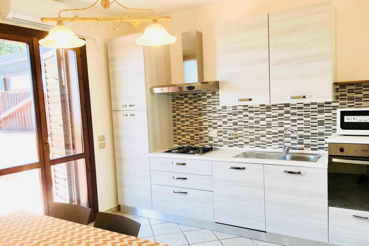 Une cuisine moderne avec des meubles blancs, un pare-feu en carrelage et un four encastré.