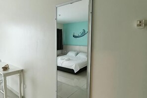 A room with a bed, a mirror, and a small table. - Peaceful 1-Bedroom Unit at Marina Island by JoMy Homestay (Manjung)