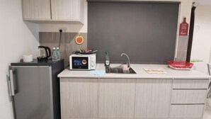 Eine kleine Küche mit Kühlschrank, Mikrowelle, Spüle und einer Arbeitsplatte.