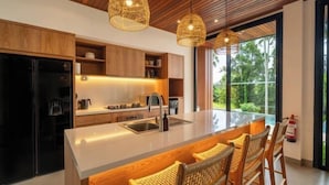 Una cocina moderna con una isla central, armarios de madera e iluminación colgante.
