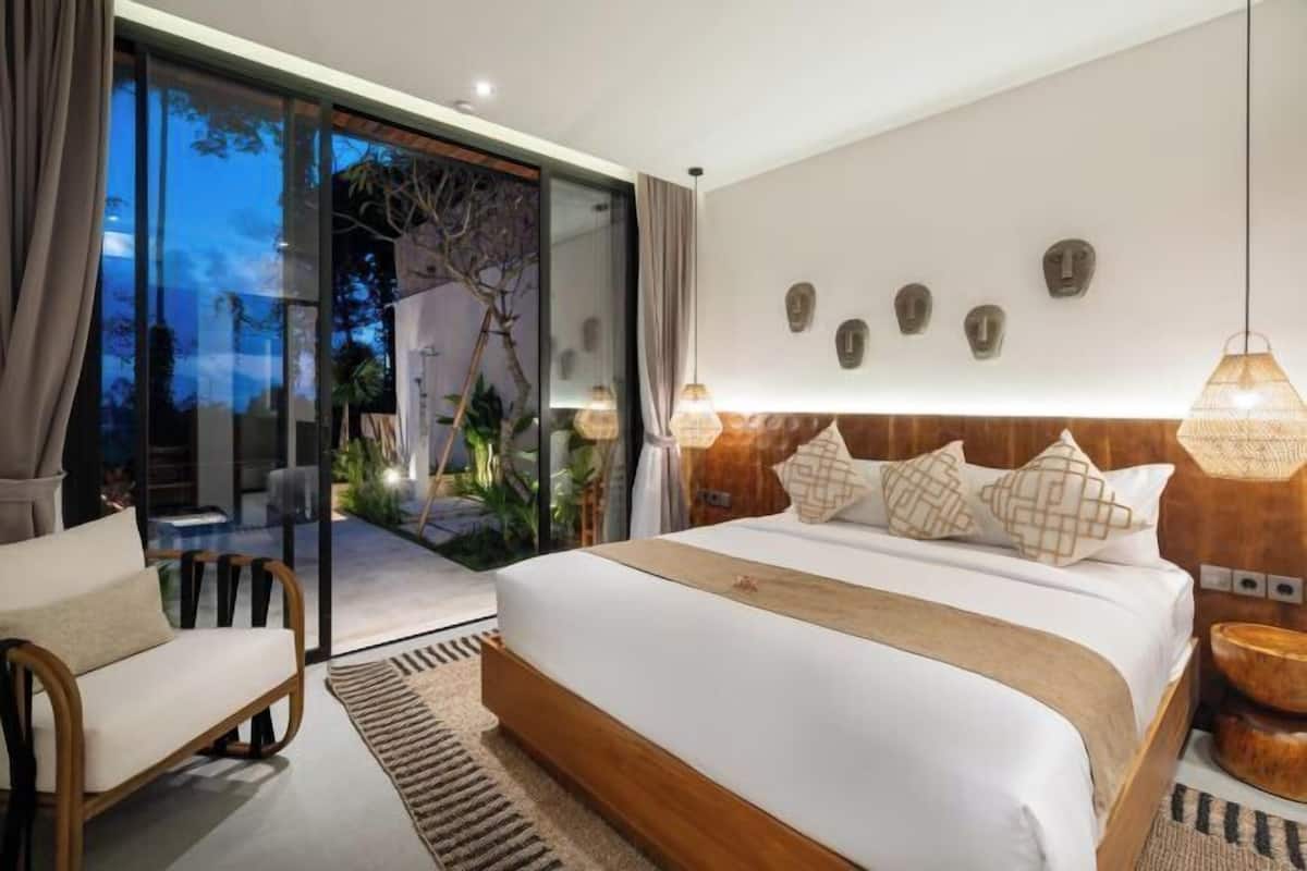 Een moderne slaapkamer met een groot bed, een glazen deur naar een buitenruimte en een houten hoofdbord.