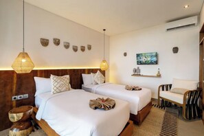 A hotel room with two beds, a wooden headboard, a woven rug, a chair, and wall-mounted artwork.
