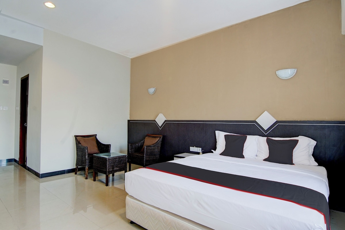 Ein Hotelzimmer mit einem großen Bett, zwei Stühlen, einem kleinen Tisch und einer Tür.