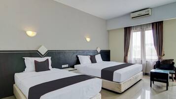 Una habitación de hotel con dos camas, una silla, un escritorio y un equipo de aire acondicionado.