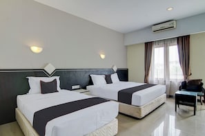 Een hotelkamer met twee bedden, een stoel, een bureau en een airconditioning.