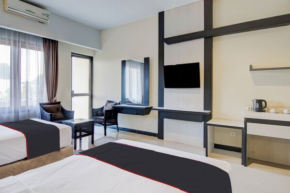 A hotel room with two beds, a desk, a chair, a TV, and a window with curtains. - Townhouse Oak Pekanbaru Near Mall Pekanbaru (Pekanbaru)
