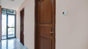 A hallway with wooden doors, a glass door leading outside, and a light switch on the wall.