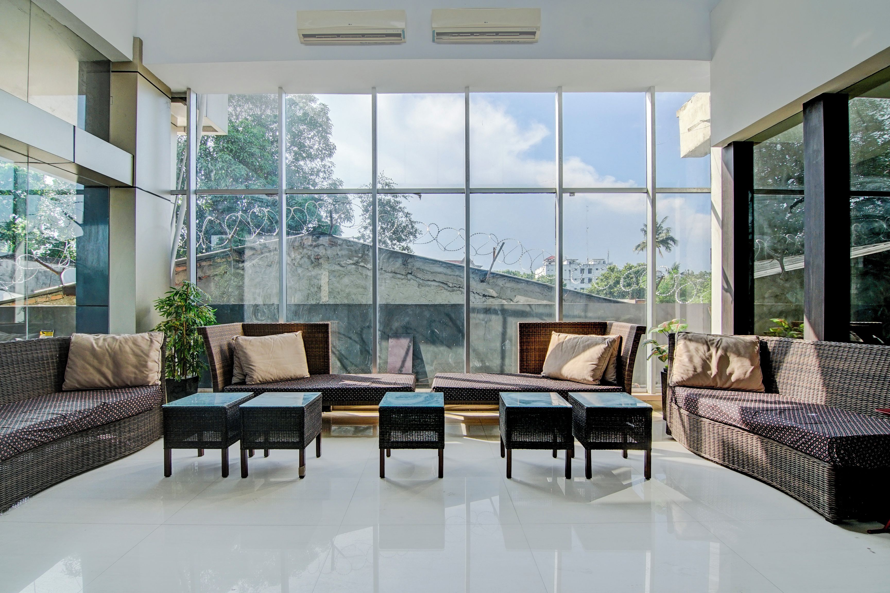 Amplio espacio interior con grandes ventanales, mobiliario de mimbre y vistas a un paisaje montañoso.