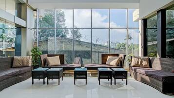 Amplio espacio interior con grandes ventanales, mobiliario de mimbre y vistas a un paisaje montañoso.