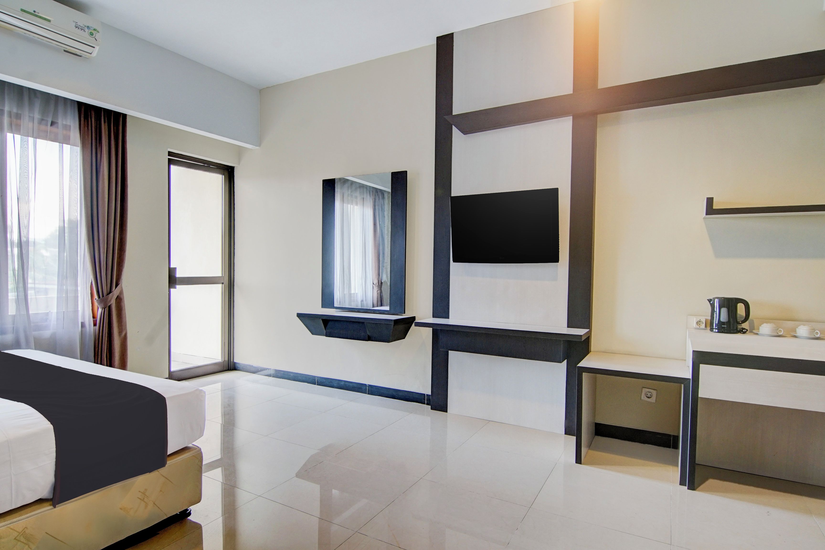 Hotelkamer met een bed, bureau, flatscreen televisie, raam met gordijnen en een wandplank.