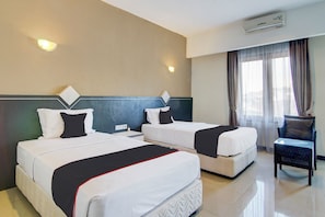 Een hotelkamer met twee bedden, een stoel, een nachtkastje en een airconditioning.