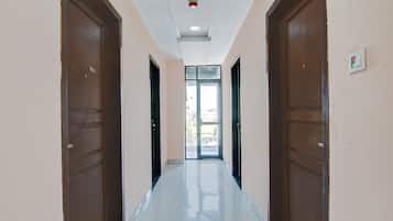A corridor with two doors on each side, a ceiling light, and a view through a glass door at the end.