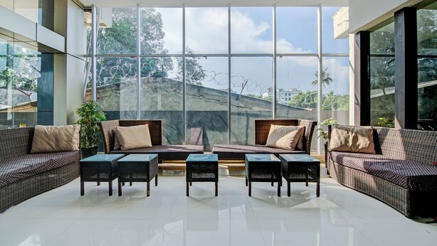 Amplio espacio interior con grandes ventanales, mobiliario de mimbre y vistas a un paisaje montañoso.