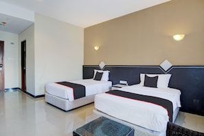 A hotel room with two beds, a small table, and a wall-mounted light fixture. - Townhouse Oak Pekanbaru Near Mall Pekanbaru (Pekanbaru)