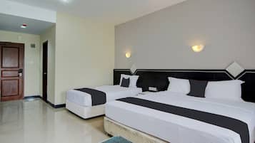 A hotel room with two beds, a wooden door, and a tiled floor.