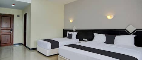 A hotel room with two beds, a wooden door, and a tiled floor.