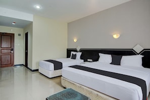 Een hotelkamer met twee bedden, een houten deur en een betegelde vloer.